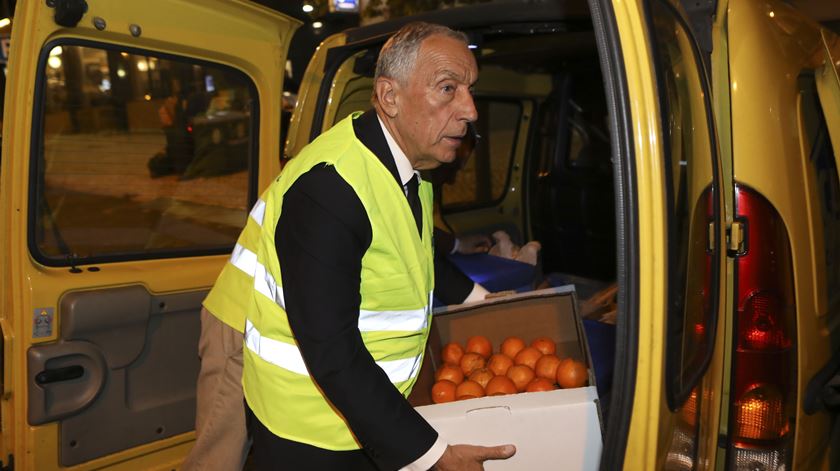 Marcelo Rebelo de Sousa  ajuda a carregar uma caixa de laranjas durante acompanhamento de voluntários do Centro de Apoio aos Sem-Abrigo. Foto: MIGUEL A. LOPES/LUSA